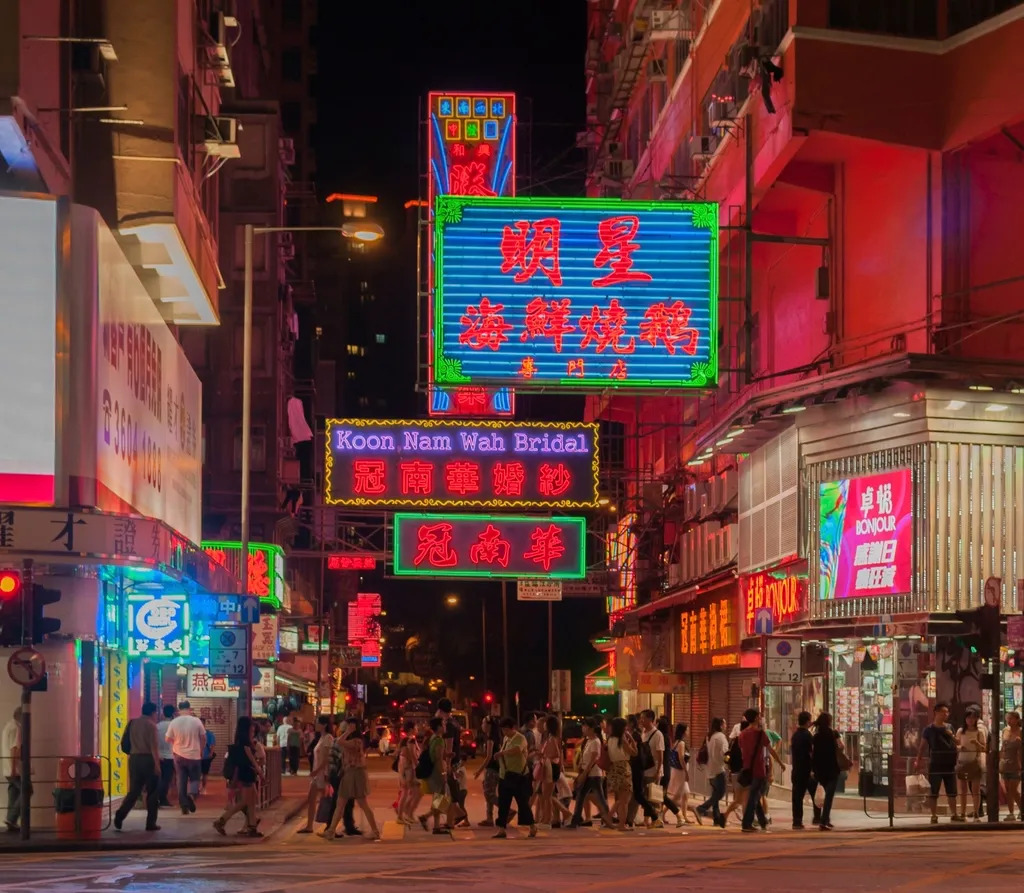 Neon shop signs over a busy Hong Kong street at night