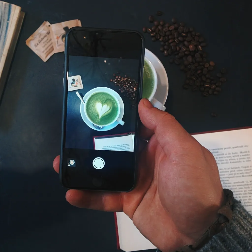 Close-up of a phone photographing a matcha latte for social media